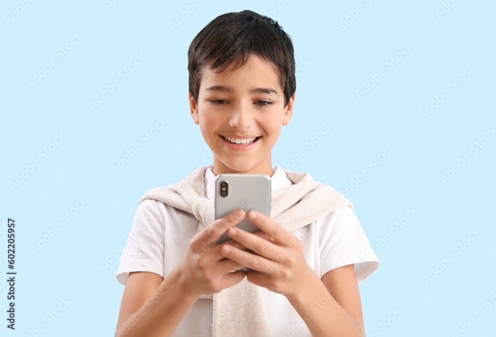Little boy using mobile phone on blue background Little boy using mobile phone on blue background
