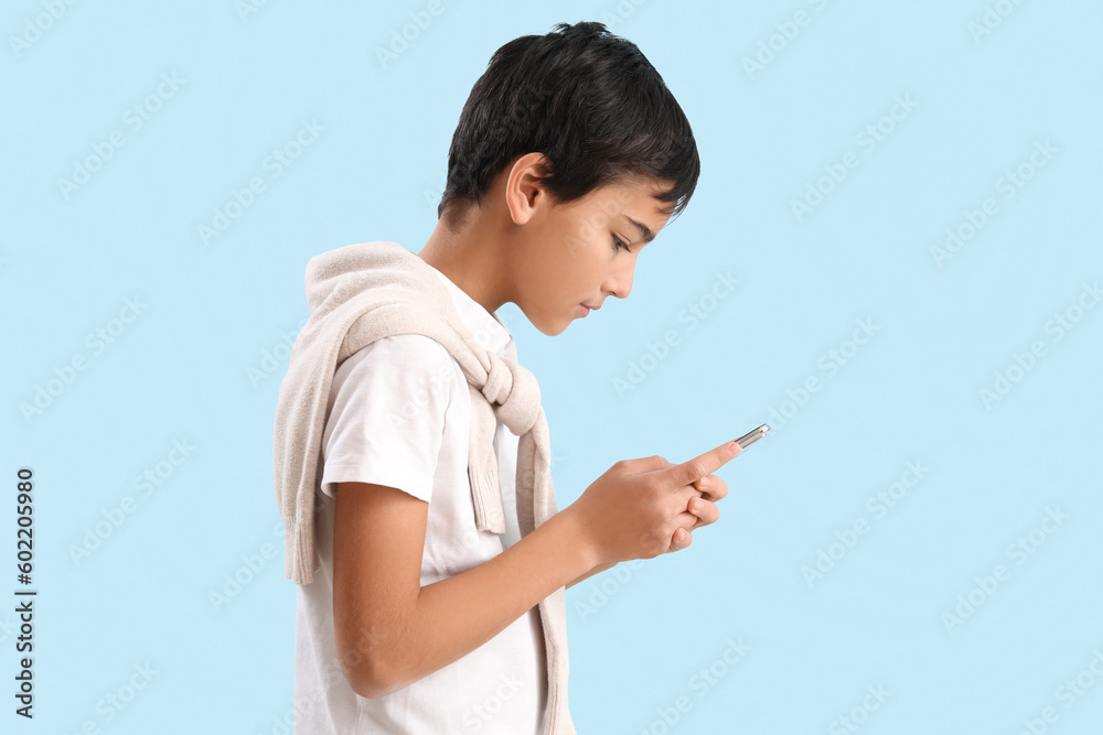 Little boy using mobile phone on blue background Little boy using mobile phone on blue background