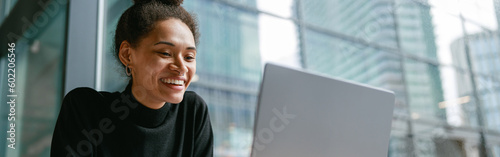 Smiling female freelancer working on laptop while sitting in cafe near window. Distance work