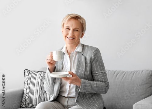 Mature businesswoman drinki...