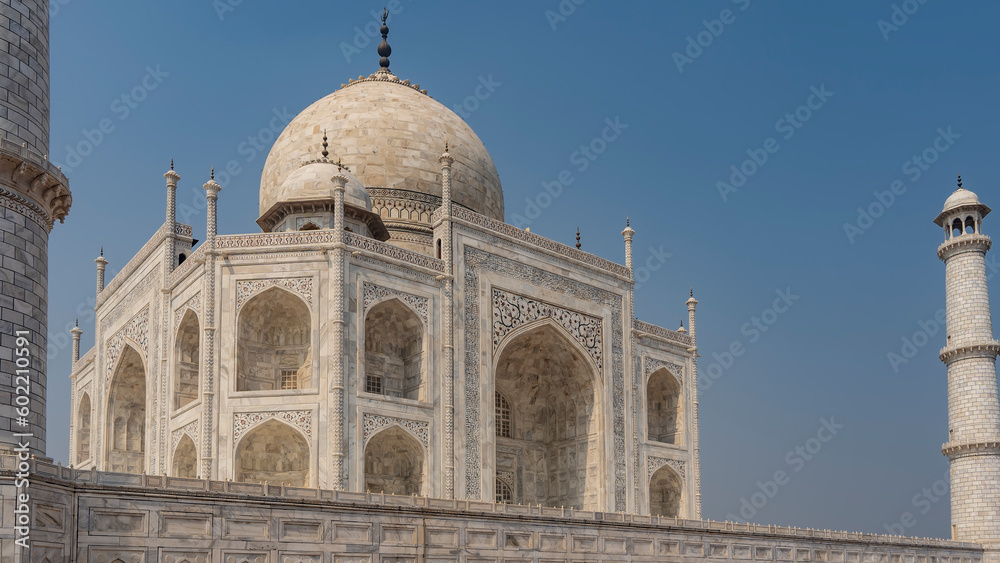 Beautiful Taj Mahal against the blue sky. Symmetrical white marble mausoleum with arches, domes, minarets. There are ornaments and inlays of precious stones on the walls. India. Agra.