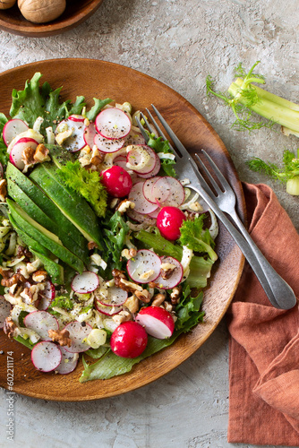 plate with salad with radish and avocado on a light table