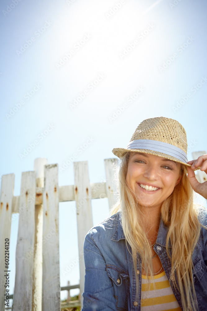Woman, hat and portrait in sunshine, blue sky background or mockup lens flare. Summer fashion, park and female relax at field fence, nature and freedom with happiness in environment, mock up or smile