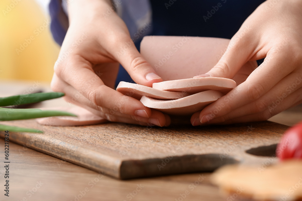 Woman holding boiled sausage at table in kitchen Woman holding boiled sausage at table in kitchen