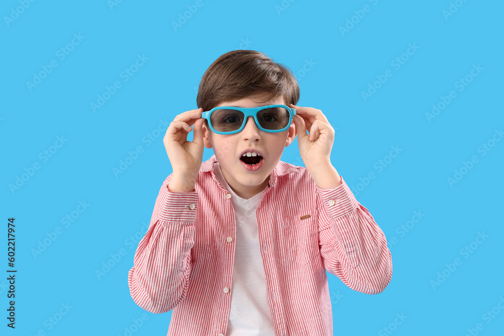 Shocked little boy in 3D glasses on blue background. Children's Day celebration
