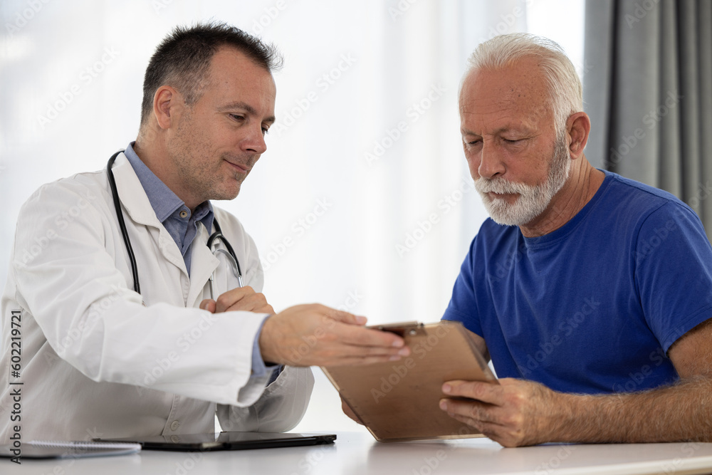 Fototapeta premium Senior man filling insurance or other legal document at appointment with doctor. Elderly patient signing medical treatment contract, agreement form for medical care service, consultation, therapy