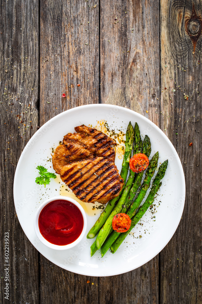 Barbecued meat and asparagus on wooden table Barbecued meat and asparagus on wooden table