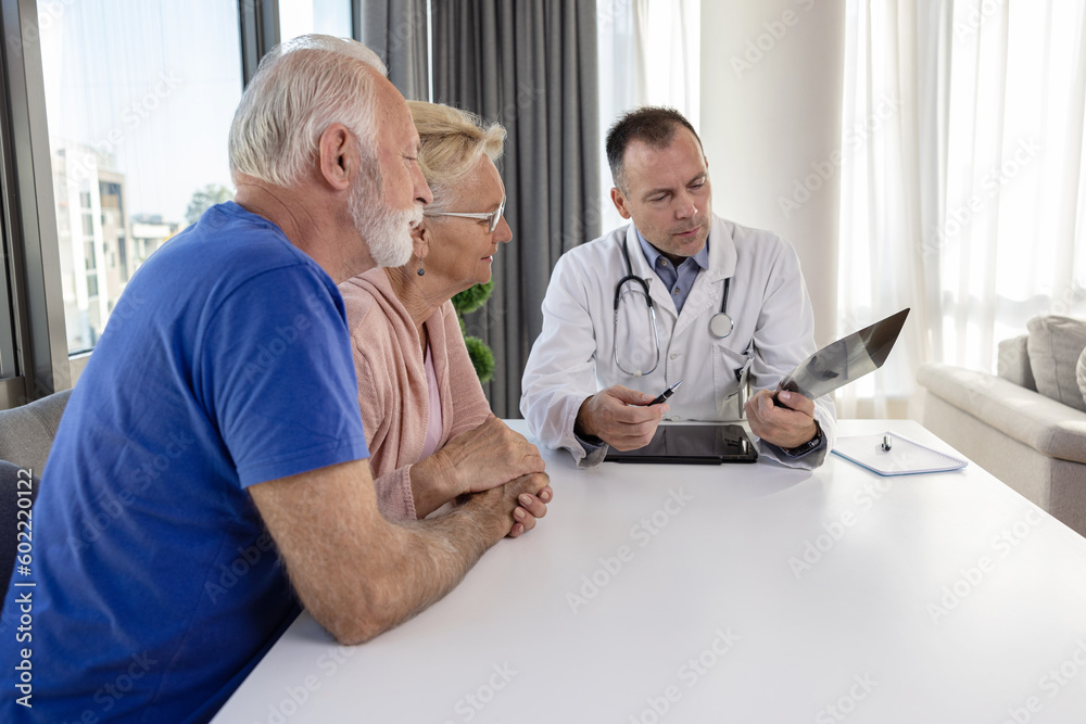 Fototapeta premium Senior couple at doctor medical consultation visit. Healthcare worker looking at x-ray print and discusses health problems with elderly spouses