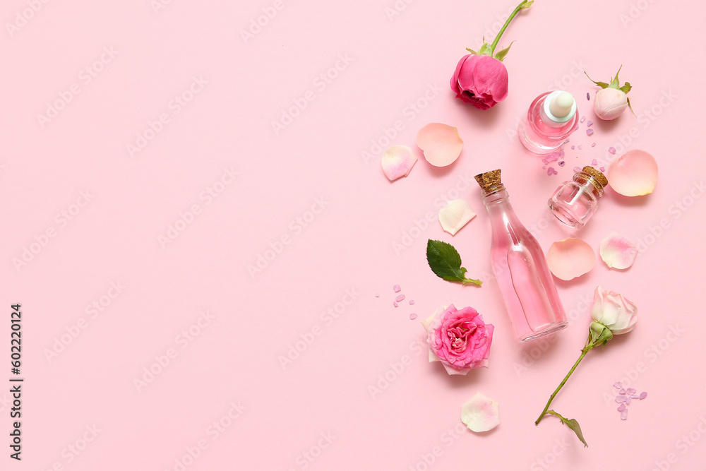 Bottles of cosmetic oil with rose extract and flowers on pink background Bottles of cosmetic oil with rose extract and flowers on pink background