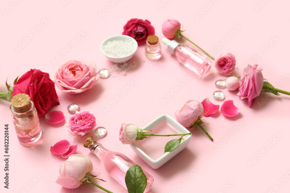 Bottles of cosmetic oil with rose extract and flowers on pink background Bottles of cosmetic oil with rose extract and flowers on pink background