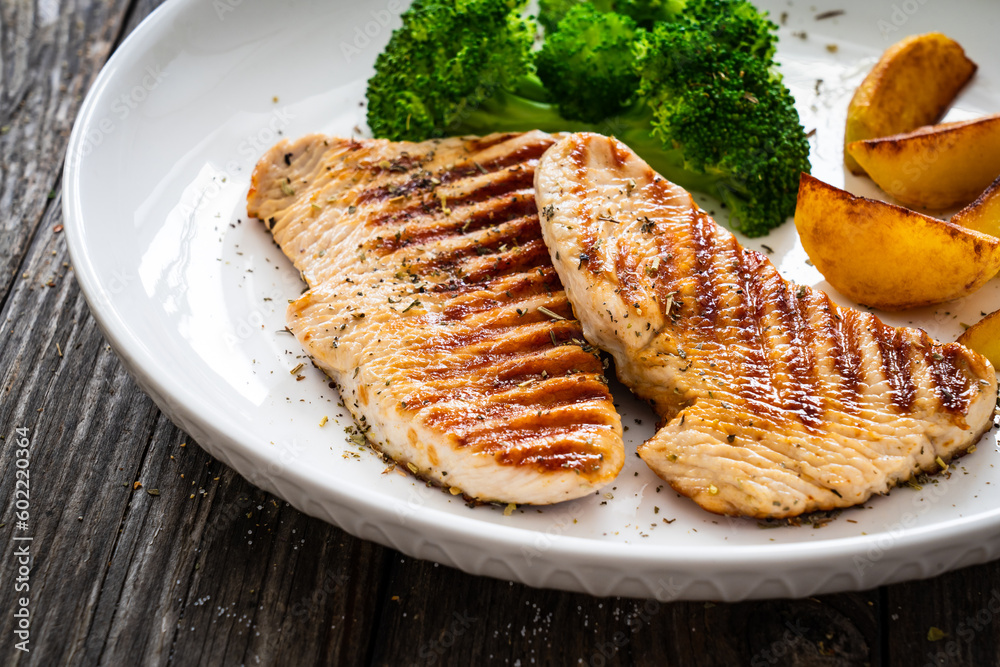 Barbecued turkey breast and broccoli on wooden table Barbecued turkey breast and broccoli on wooden table