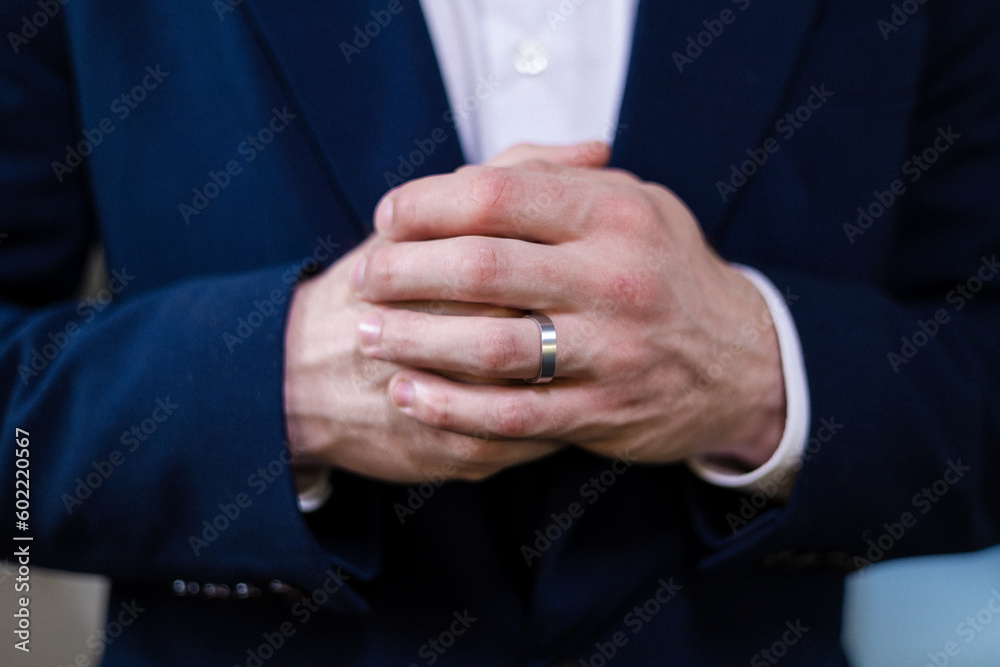 Closeup shot in a jewelry boutique man's hand adorned with a wedding ring from yellow and white gold. Focus is on the ring, groom's wedding day, engagement of the couple.