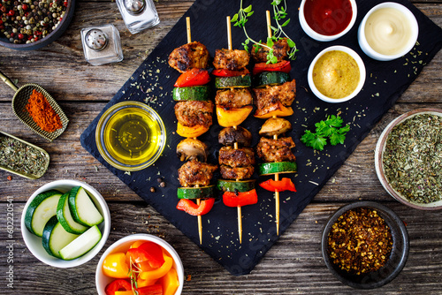 Meat skewers - grilled meat with vegetables on wooden background

