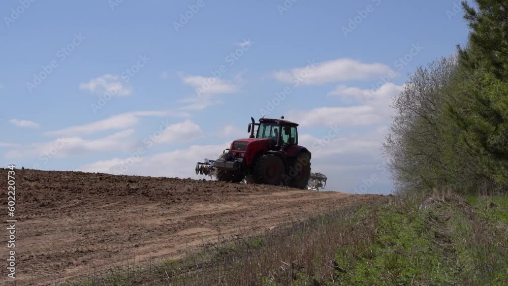 Tractor on the farmer's field plows and cultivates the soil. Agriculture, farming business harvest concept. Tractor on the farmer's field plows and cultivates the soil. Agriculture, farming business harvest concept.
