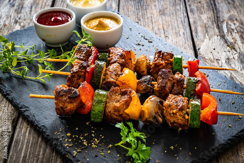 Meat skewers - grilled meat with vegetables on wooden background
