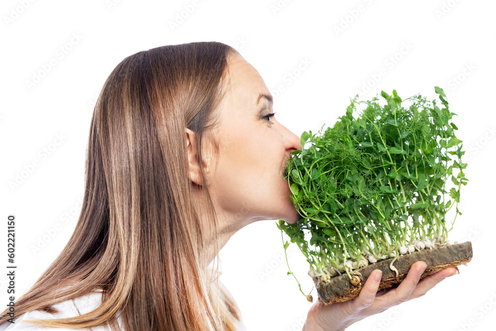 Young woman eating pea microgreens. Eco food and vitamins. Isolated on white background. Side view. Young woman eating pea microgreens. Eco food and vitamins. Isolated on white background. Side view.
