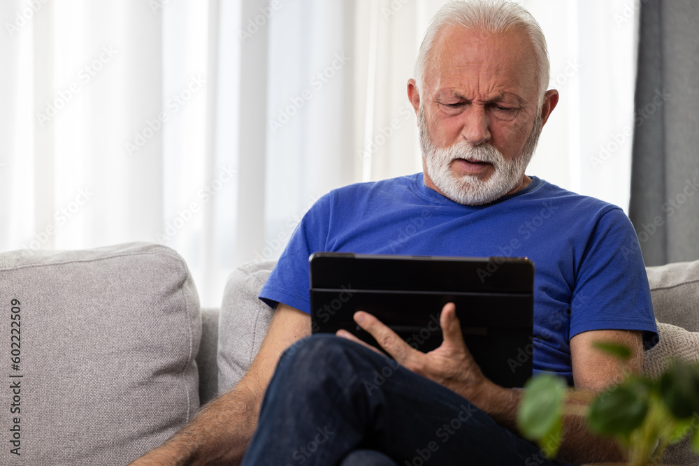 Shocked frustrated senior mature man reading shocking online news at home. Stressed worried elderly male confused by bad news or computer problem Shocked frustrated senior mature man reading shocking online news at home. Stressed worried elderly male confused by bad news or computer problem