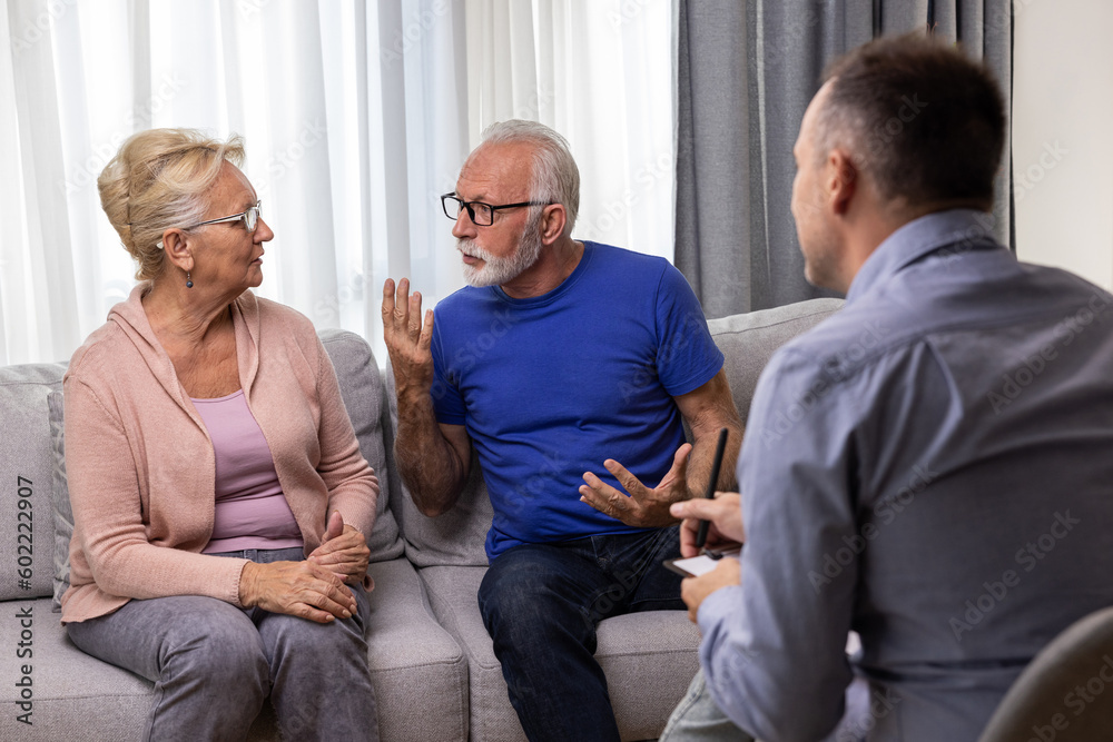 Unhappy senior couple arguing, having fight, disagreement at psychologists office. Frustrated elderly wife and husband discussing relationship problems with their therapist Unhappy senior couple arguing, having fight, disagreement at psychologists office. Frustrated elderly wife and husband discussing relationship problems with their therapist