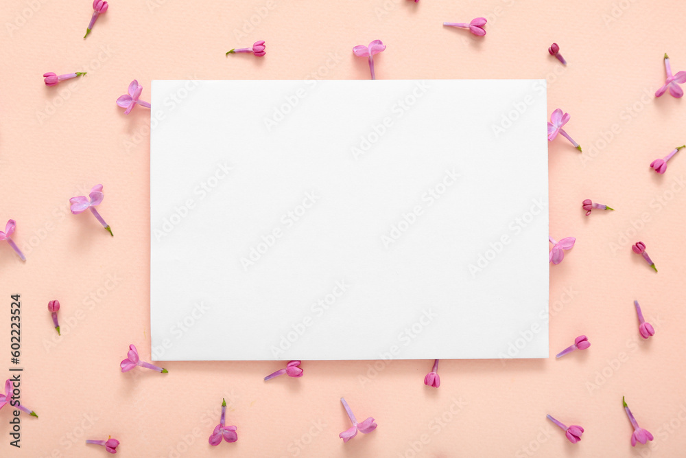 Blank card and beautiful lilac flowers on pale pink background