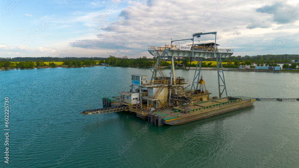 Industrial boat floating on the lake. Boat in the middle of the lake. Water background. Boat from mining industry. Industrial boat floating on the lake. Boat in the middle of the lake. Water background. Boat from mining industry.