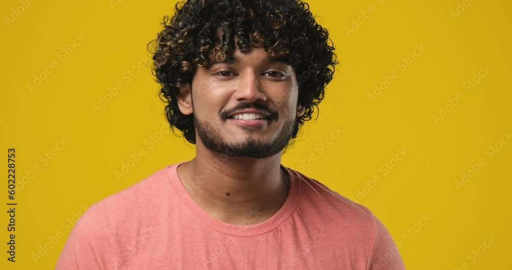 Young indian man satisfied happy guy standing over orange background Young indian man satisfied happy guy standing over orange background