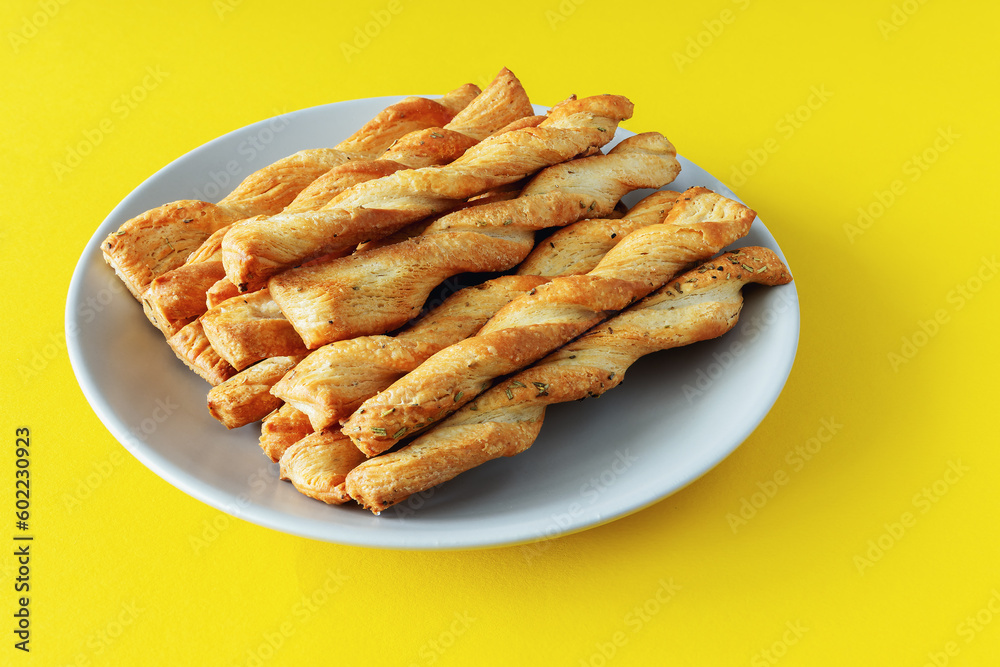 Sticks of buttery yeast dough on a plate on a yellow background Sticks of buttery yeast dough on a plate on a yellow background