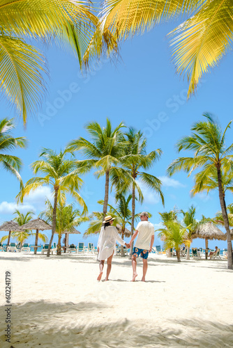 Palm Beach Aruba Caribbean, a couple of men and women at a white long sandy beach with palm trees at Aruba Antilles. © Fokke Baarssen