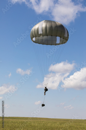 Un soldado paracaidista aterriza en el campo con su equipo.