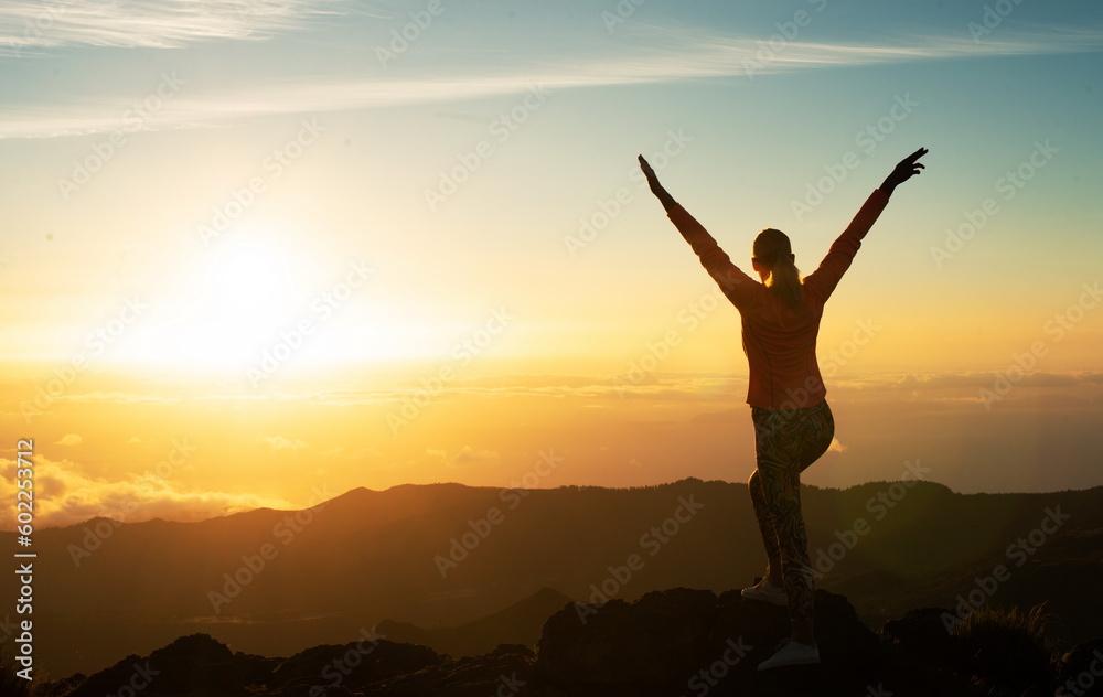 Woman Standing On Top Of Mountain Raising Arms, Back View Woman Standing On Top Of Mountain Raising Arms, Back View