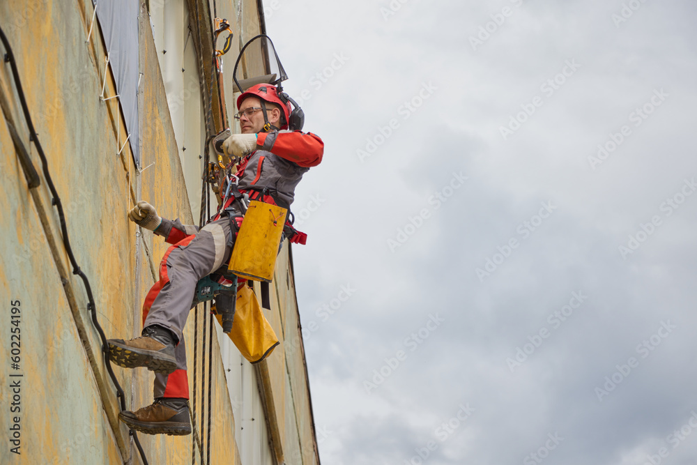 Obraz premium Rope access is a high-risk job. A man works on ropes.