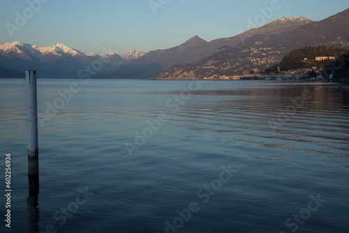 Como Lake. Portion of Lake with snowy mountains  coast  a ferry  and little hamlet in the distance in sunset time.