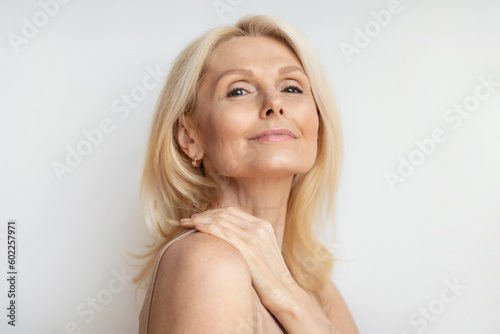 Portrait of attractive senior woman with bare shoulders, perfect skin and natural makeup posing over white background