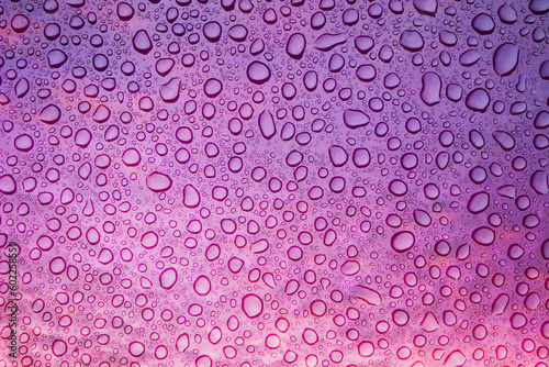 Texture with water drops on a purple background. Purple rain drops on the sky window glass