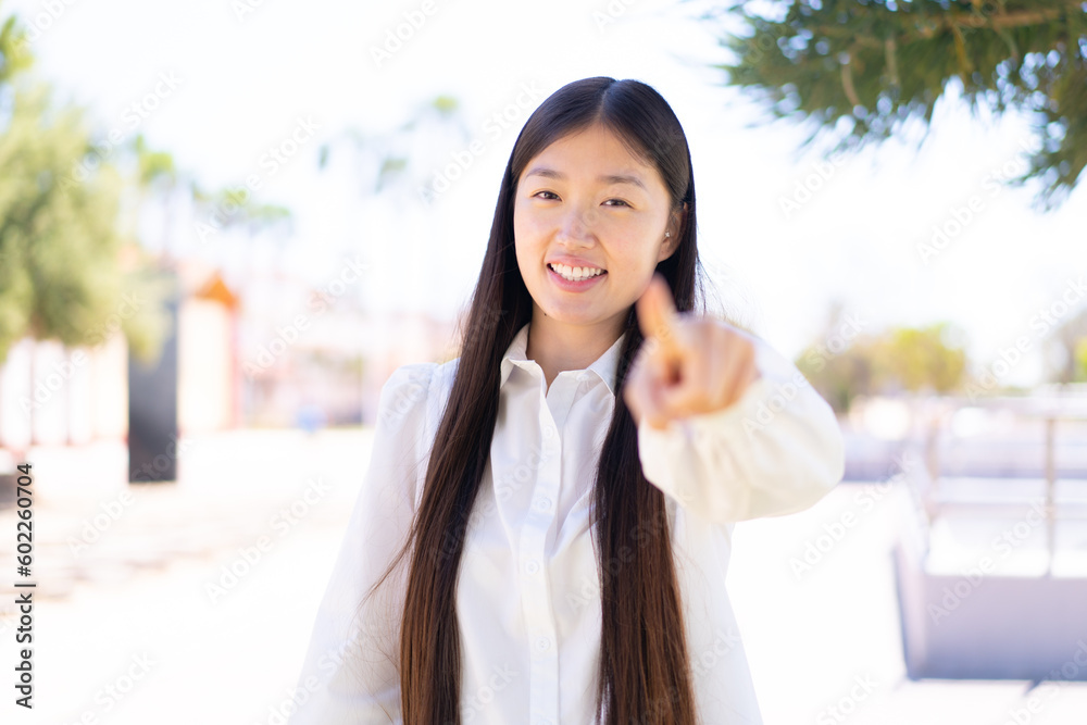 Pretty Chinese woman at outdoors points finger at you with a confident expression Pretty Chinese woman at outdoors points finger at you with a confident expression