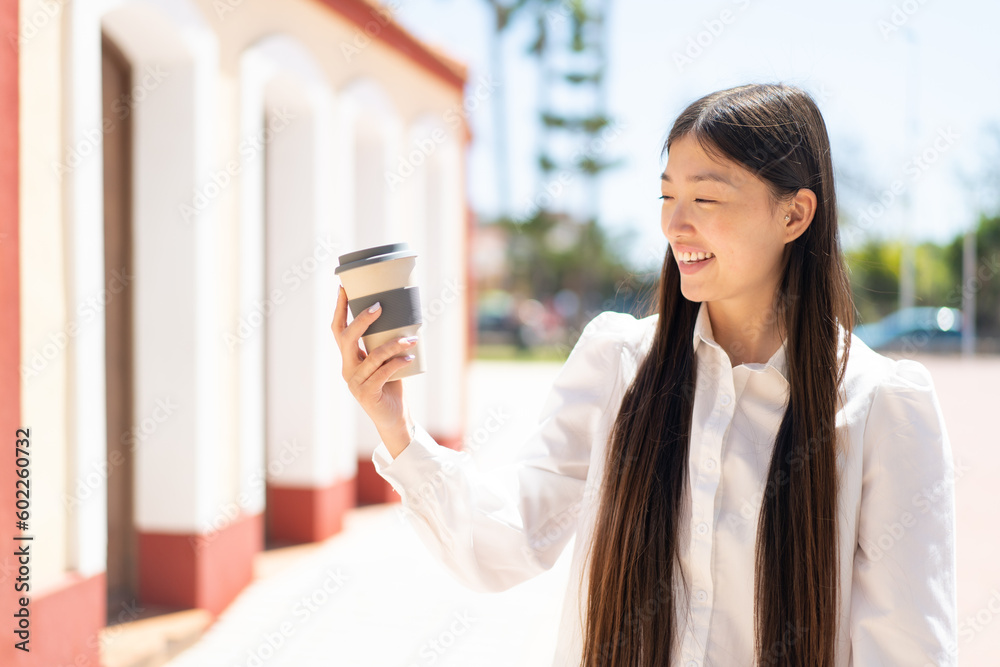 Pretty Chinese woman holding a take away coffee at outdoors with happy expression Pretty Chinese woman holding a take away coffee at outdoors with happy expression