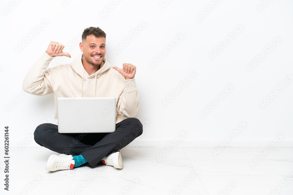 Young caucasian man with a laptop sitting on the floor isolated on white background proud and self-satisfied Young caucasian man with a laptop sitting on the floor isolated on white background proud and self-satisfied