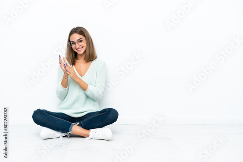 Young caucasian woman sitting on the floor isolated on white background applauding after presentation in a conference