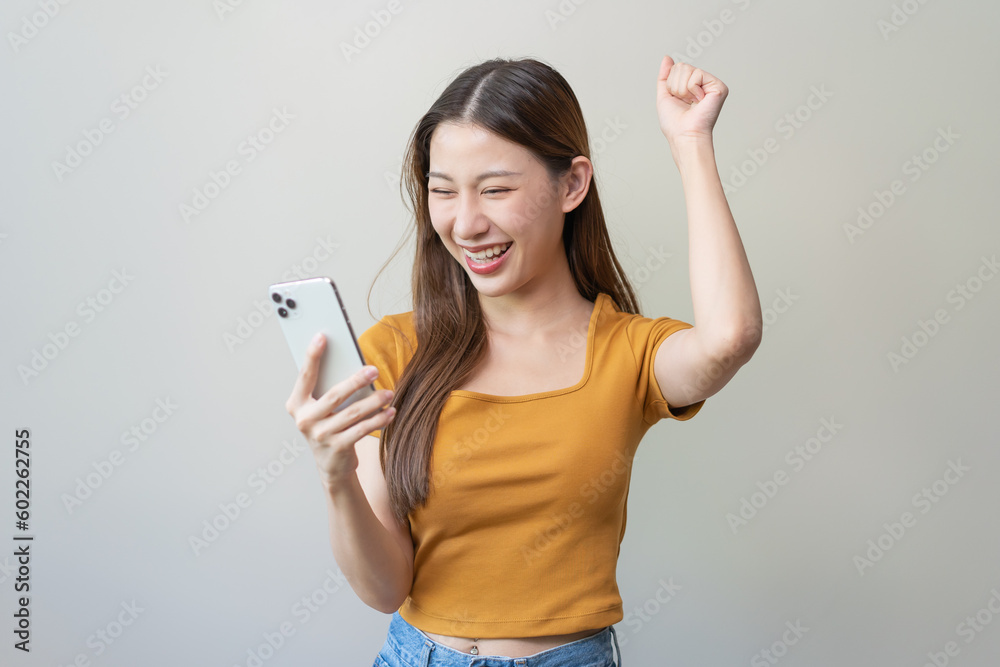 Happy Asian woman holding a smartphone and winning the prize. Happy Asian woman holding a smartphone and winning the prize.