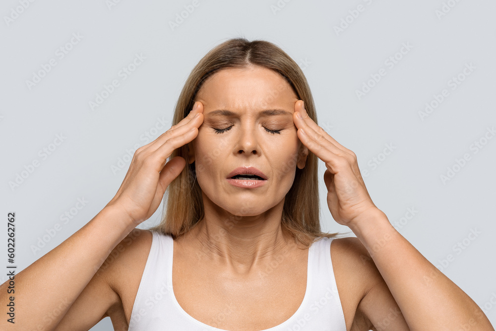 Blonde woman with closed eyes rubbing temples Blonde woman with closed eyes rubbing temples