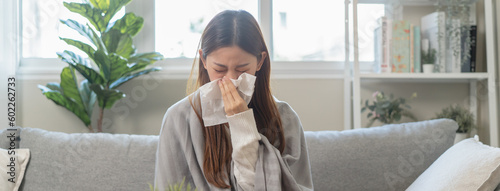 Seasonal sick concept. the young woman has a common cold and sneezing on the sofa. photo