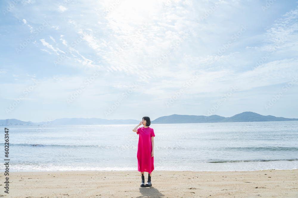 晴天の海を散策する女性