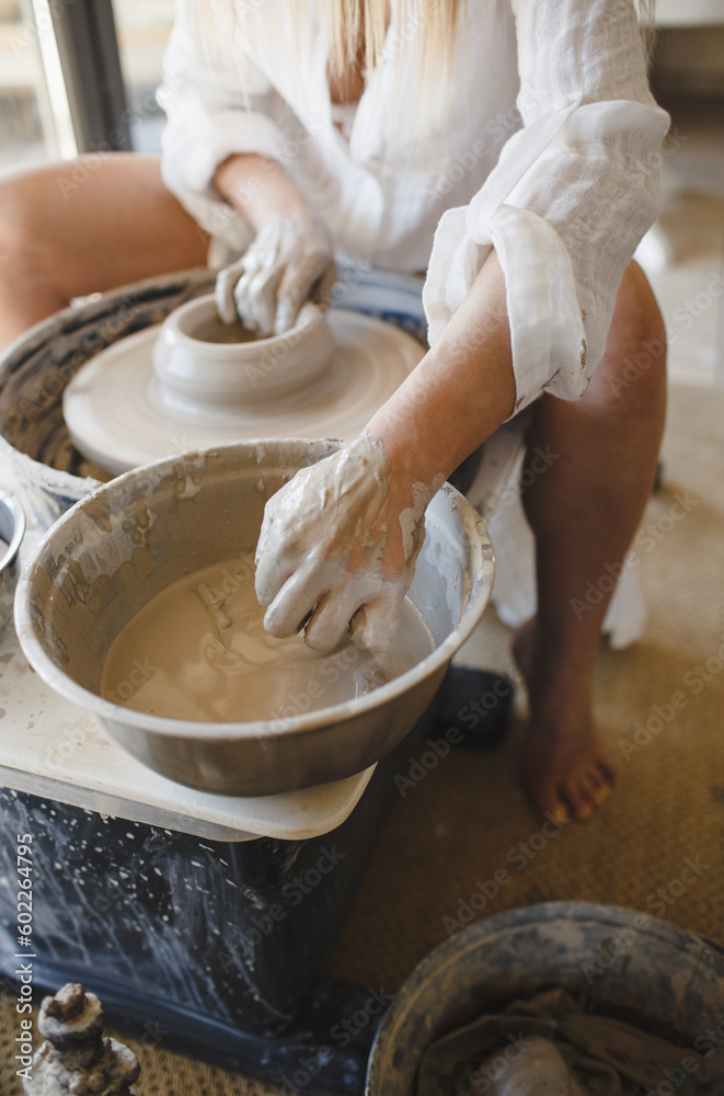 A woman works behind a potter's wheel. Creating handmade tableware