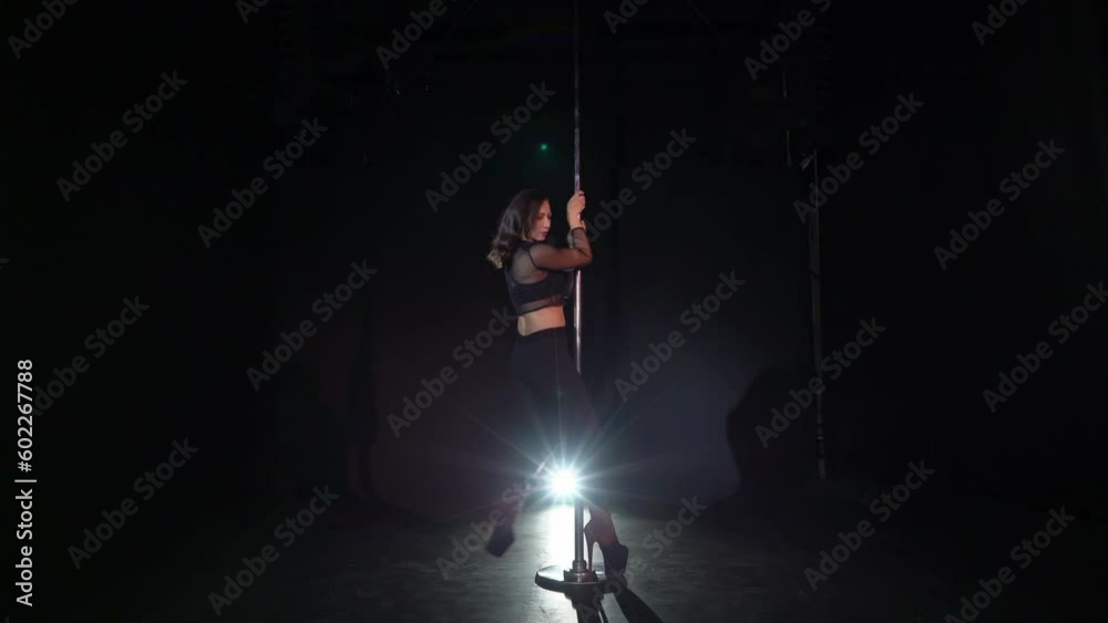 Pole dance. Young beautiful caucasian brunette woman dancer in studio.