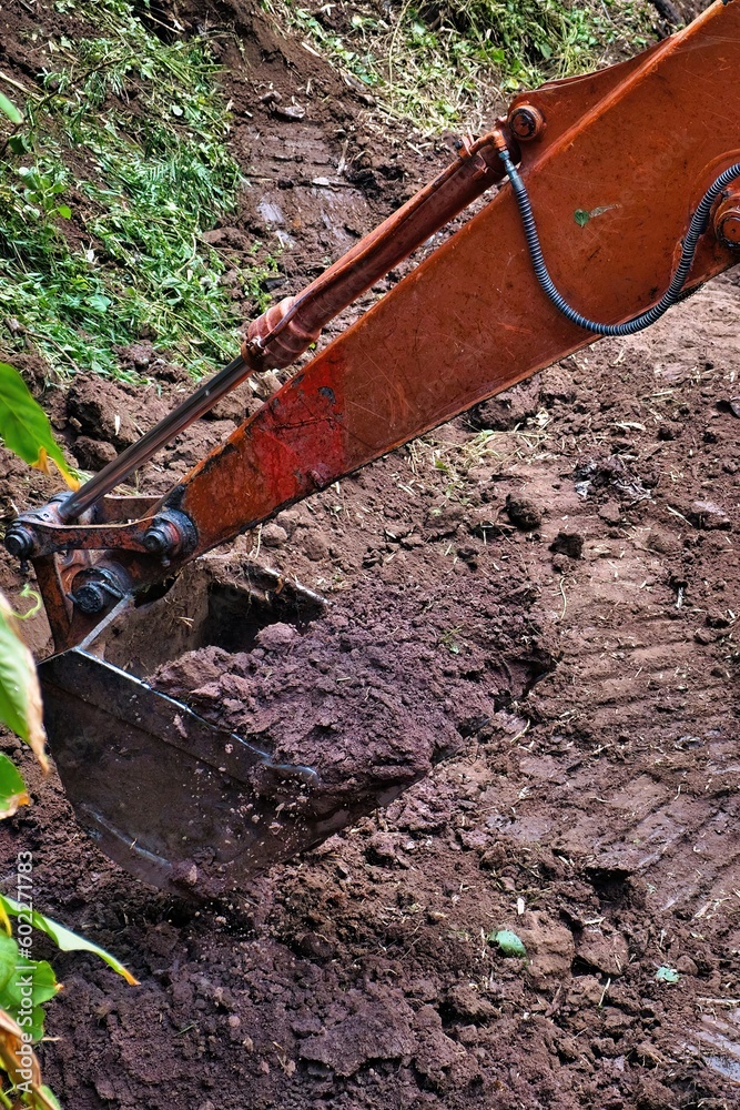 Fototapeta premium Shovel excavator moving a pile of rich brown soil