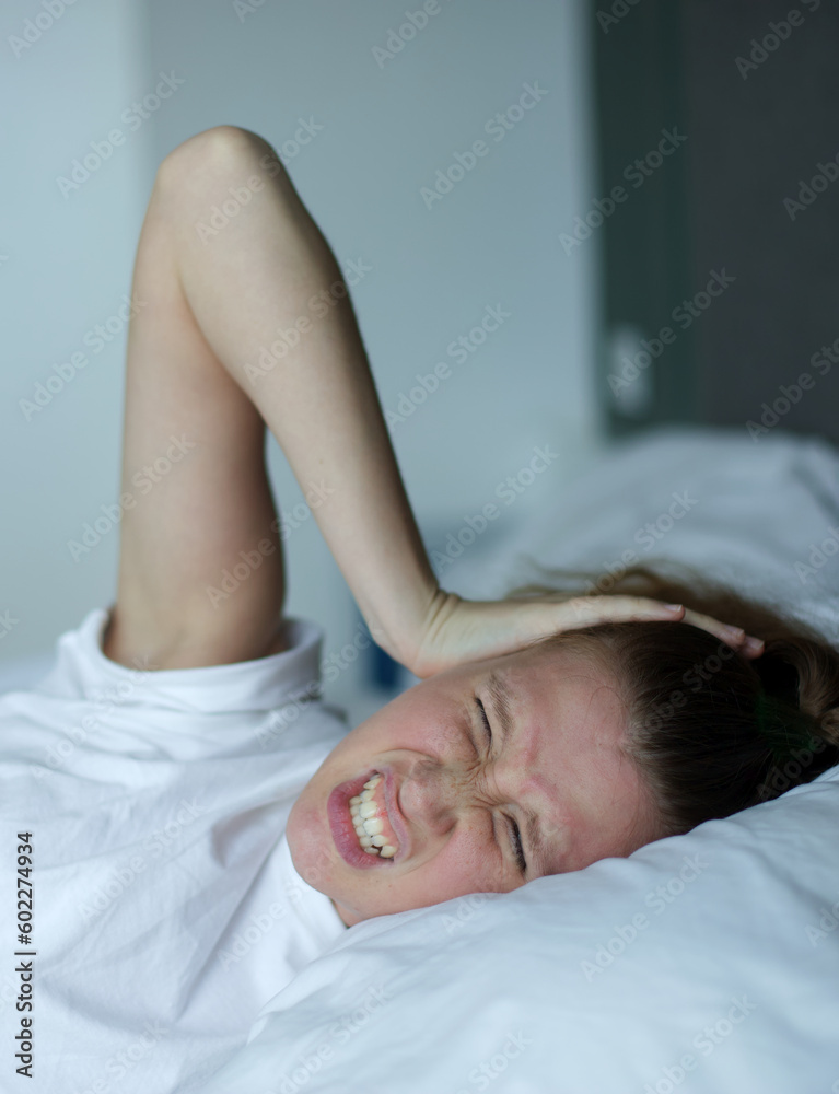Young sad depressed unhappy worried woman in the bed in bedroom at home in the morning and feel angry neighbors are noisy, lying under white blanket suffer from insomnia problems with sleep at night Young sad depressed unhappy worried woman in the bed in bedroom at home in the morning and feel angry neighbors are noisy, lying under white blanket suffer from insomnia problems with sleep at night