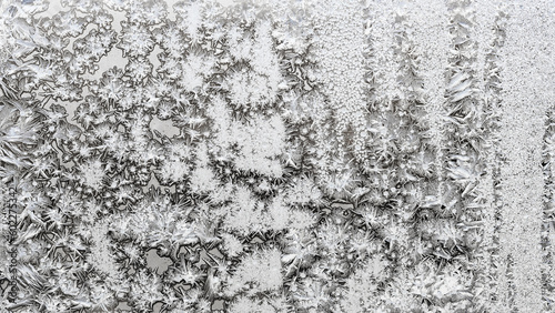 panoramic natural background - monochrome frozen pattern on surface on home window glass close up on cold winter day © vvoe