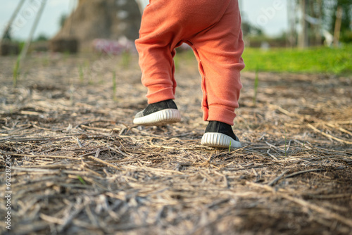 A kid is practice walking or running on soil ground at playground, close-up and selective focus at foot. People in recreation action scene.
