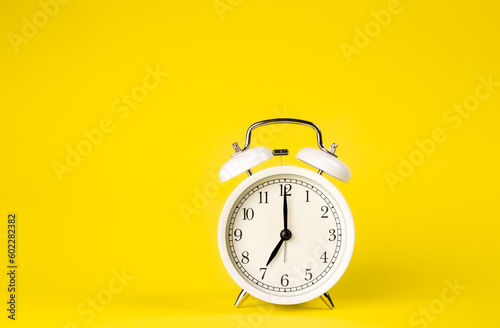 White alarm clock on a yellow background isolated, close-up.