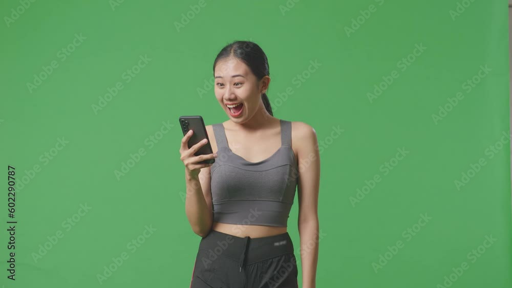 Asian Woman Wearing Sportswear And Looking At Smartphone Then Screaming Goal Celebrating On Green Screen Background In The Studio
Asian Woman Wearing Sportswear And Looking At Smartphone Then Screaming Goal Celebrating On Green Screen Background In The Studio