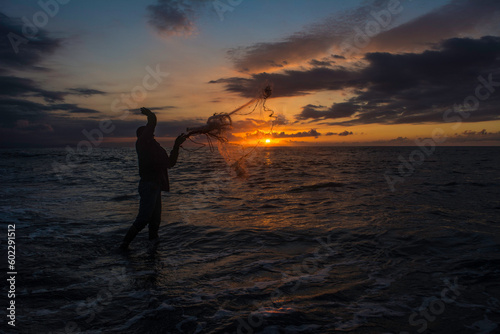 Throwing fishing net during sunset, Silhouette of man catching the fish in twilight in Africa Like Thailand, Silhouette of traditional fishermen throwing net fishing lake at sunset time. beach.